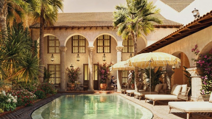 Patio interior de un hotel boutique de estilo colonial con piscina, arcos y palmeras