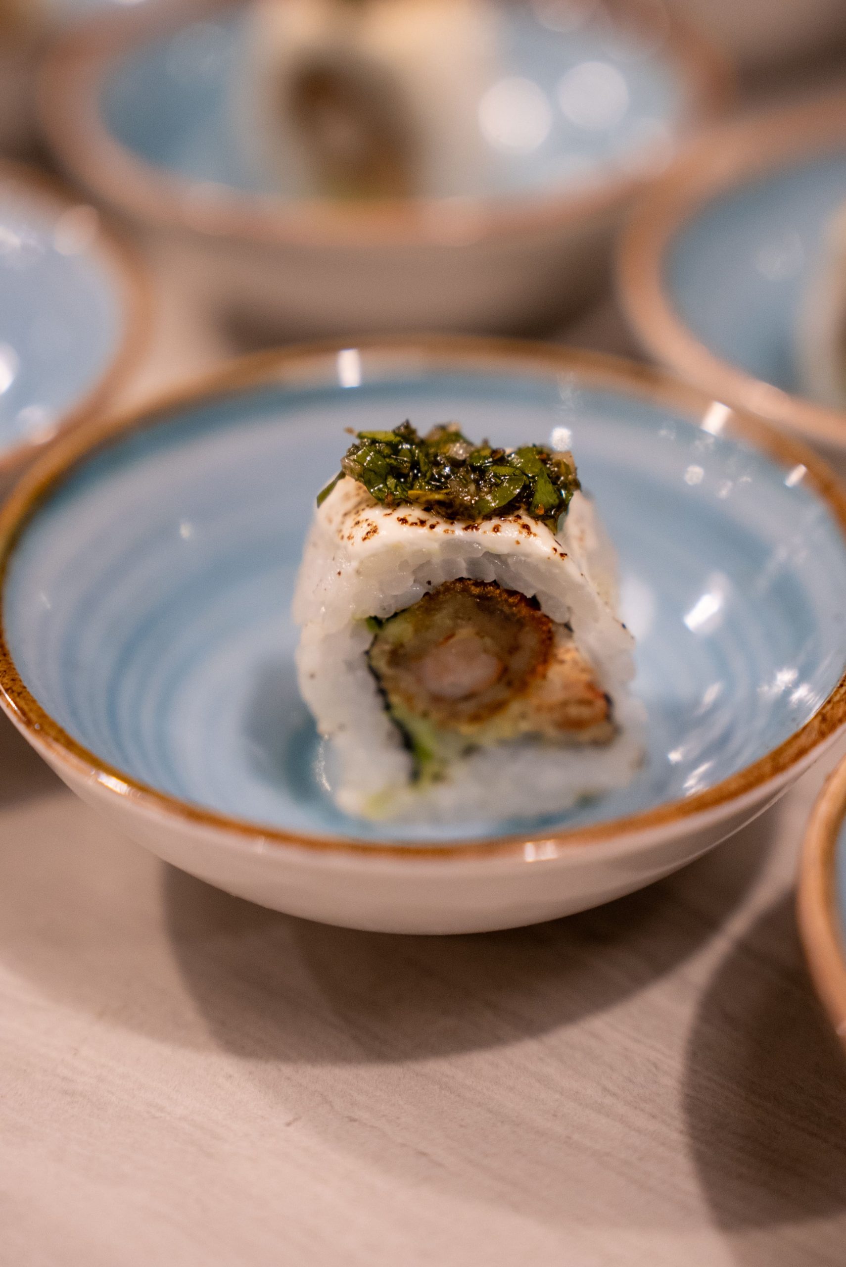 Maki de autor de Brisas Nikkei elaborado con producto marino y acabado con hierbas, servido en un cuenco de cerámica