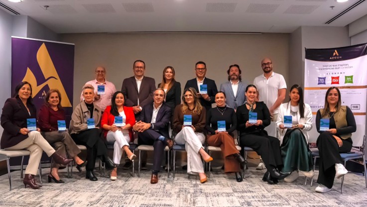 Grupo de personas posando de pie y sentadas con folletos azules frente a banners de Accor