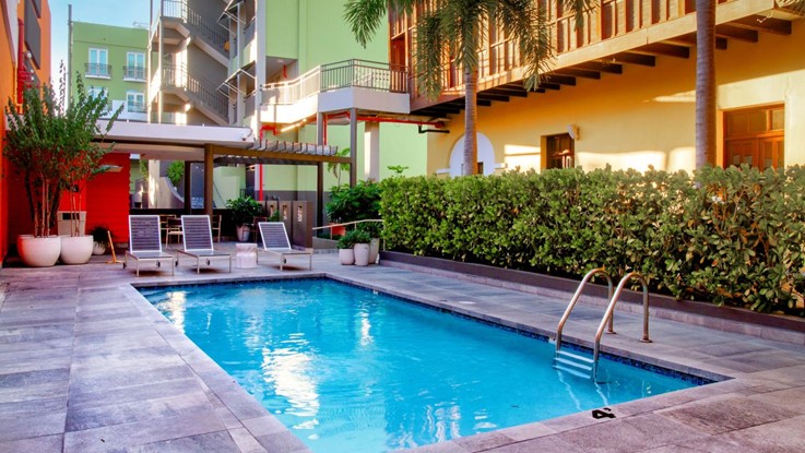 Piscina rodeada de tumbonas, plantas y edificios de colores en un hotel de estilo colonial