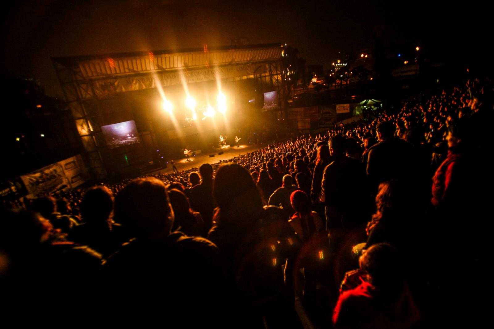 Multitud de espectadores ante un escenario iluminado durante un concierto nocturno al aire libre