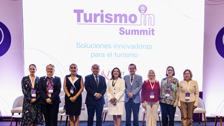 Grupo de diez participantes posando frente a la pantalla de Turismo In Summit, Soluciones innovadoras para el turismo